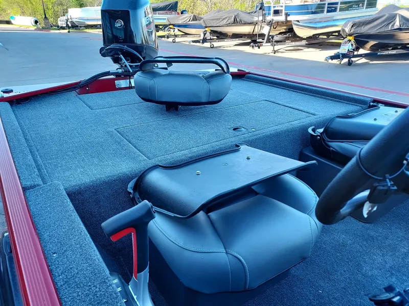Slide: The Image of 2025 Tracker Bass Tracker Classic XL boat interior with seating and motor, parked outdoors. - 2