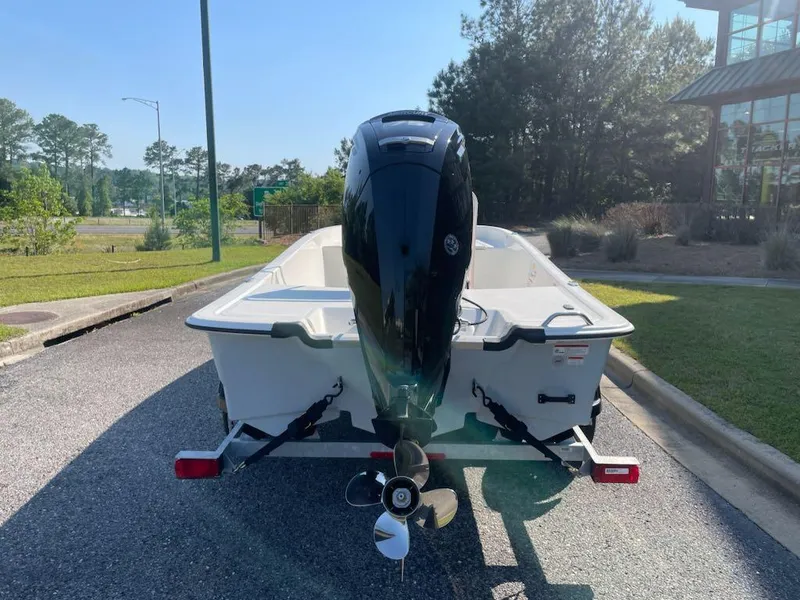 Slide: The Image of 2025 Mako Pro Skiff 17 CC boat with outboard motor, parked outdoors. - 2