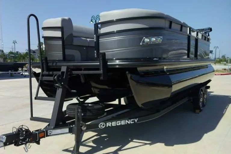 Slide: The Image of 2024 Regency 230 DL3 pontoon boat on trailer, sleek design, outdoor setting. - 1