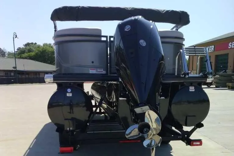 Slide: The Image of 2024 Regency 230 DL3 pontoon boat with powerful outboard motor, parked outdoors. - 2