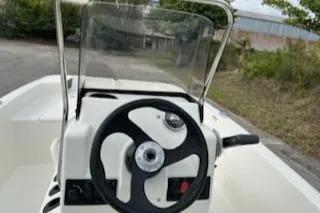 Slide: The Image of 2025 Mako Pro Skiff 15 CC boat console with steering wheel and windshield. - 4