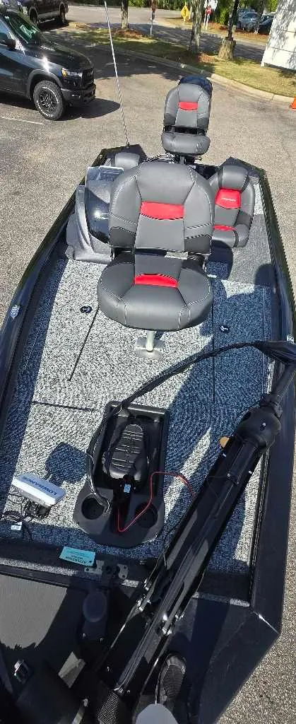 Slide: The Image of 2025 Tracker Pro Team 175 boat with gray and red seating, parked outdoors. - 2