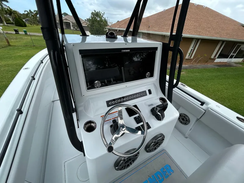 Slide: The Image of 2024 Contender 28 Tournament boat console with steering wheel and controls, docked on grass. - 22