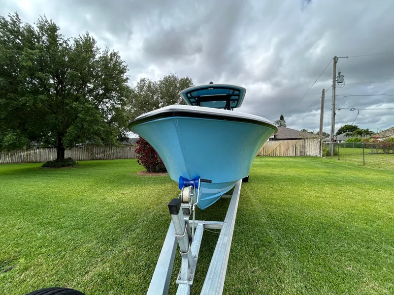 Slide: The Image of 2024 Contender 28 Tournament boat on trailer, parked on green lawn under cloudy sky. - 3