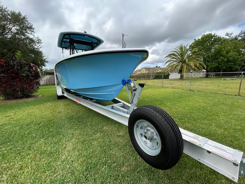 Slide: The Image of 2024 Contender 28 Tournament boat on trailer, parked on grass under cloudy sky. - 4