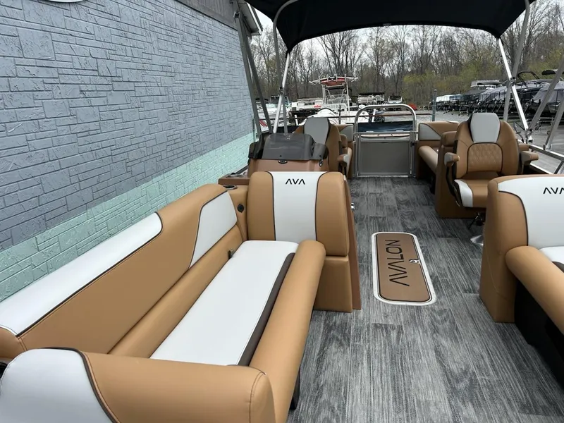 Slide: The Image of 2025 Avalon 2380 Venture Quad Lounger with tan and white seating, docked near a brick wall. - 6