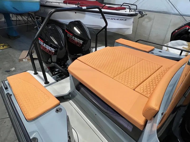 Slide: The Image of 2022 BRABUS Shadow 500 Cabin with orange seating and dual engines in a showroom. - 14