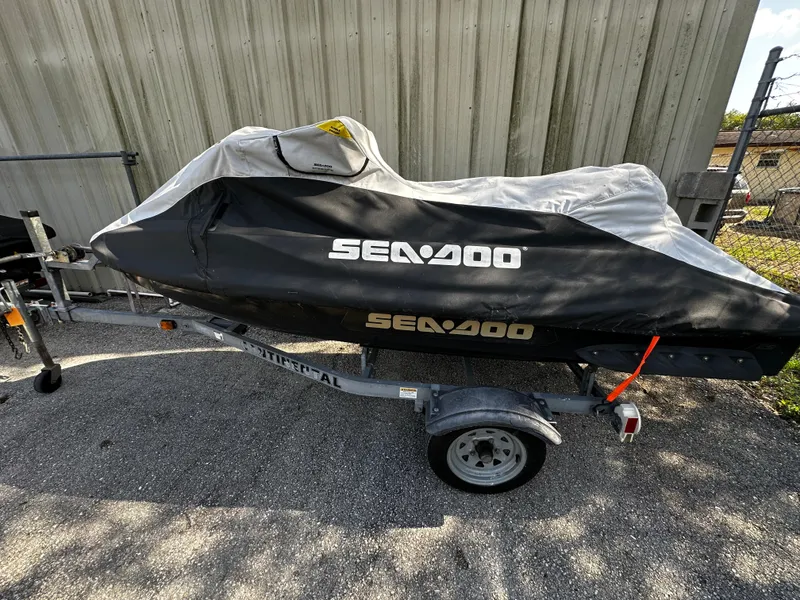 Slide: The Image of 2012 Sea-Doo GTX 155 jet ski covered on a trailer, parked outdoors. - 13