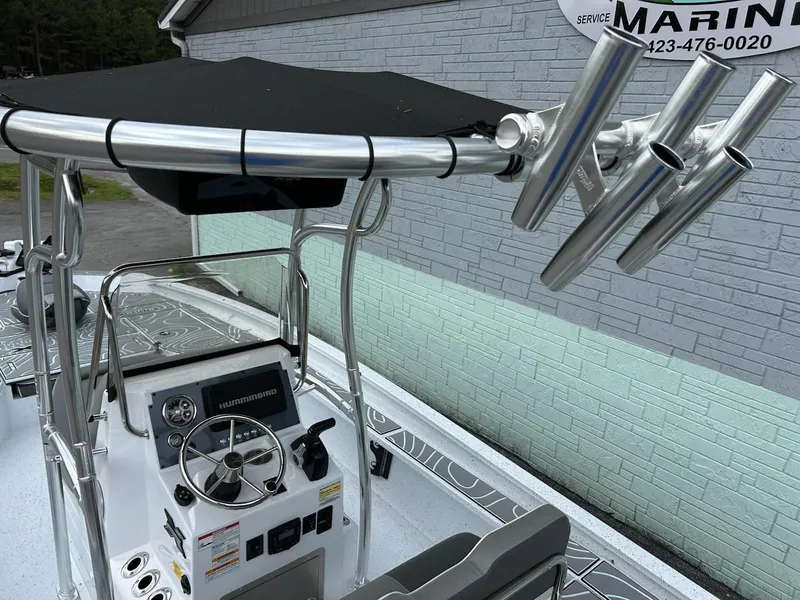 Slide: The Image of 2024 Express X23 Bay Lounge boat with steering console and rod holders, docked near a marine service. - 10