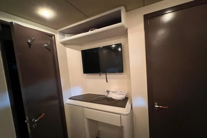 Slide: The Image of Interior of Falcon 106 yacht, featuring a wall-mounted TV and storage area, 2001 model. - 25