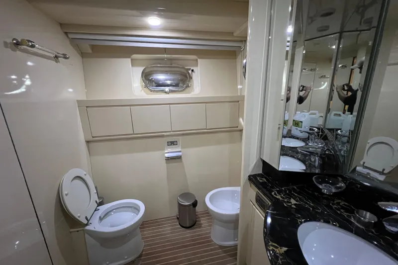 Slide: The Image of Luxurious yacht bathroom with dual toilets, marble countertop, and porthole window in Falcon 106, 2001. - 36
