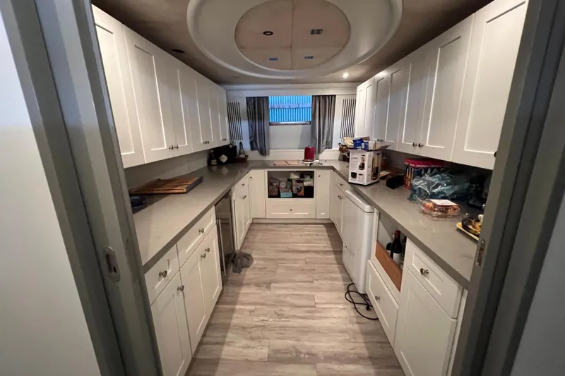 Slide: The Image of Narrow kitchen with white cabinets, modern appliances, and wood flooring in a Falcon 106, 2001 model. - 40