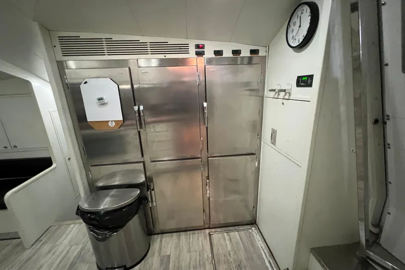 Slide: The Image of Galley kitchen with stainless steel appliances, clock, and trash can in a Falcon 106 yacht. - 42