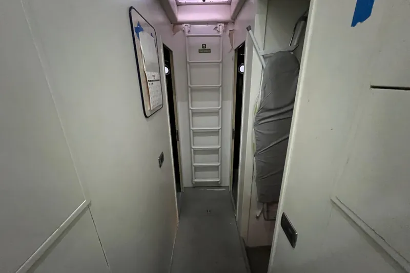 Slide: The Image of Narrow corridor inside a 2001 Falcon 106 yacht, featuring a ladder and storage area. - 44
