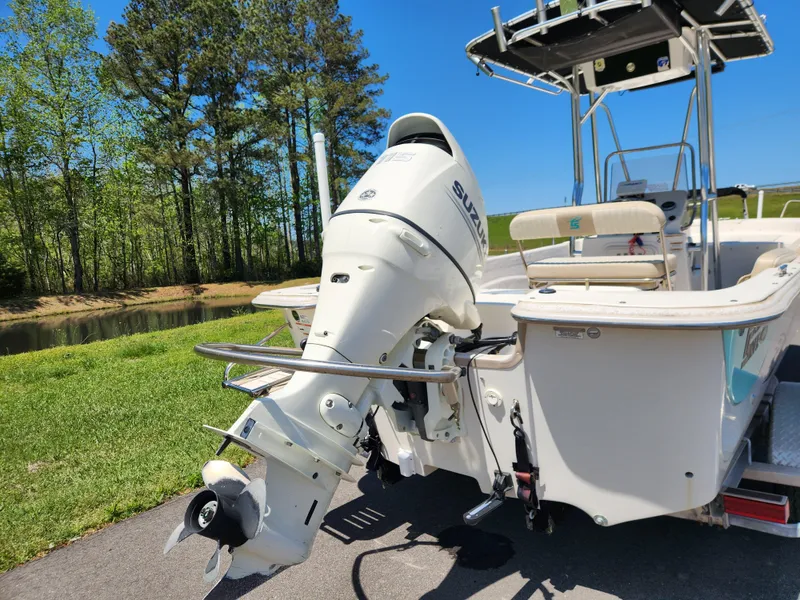 Slide: The Image of 2018 Carolina Skiff 218 DLV boat with Suzuki outboard motor, parked near a pond. - 3