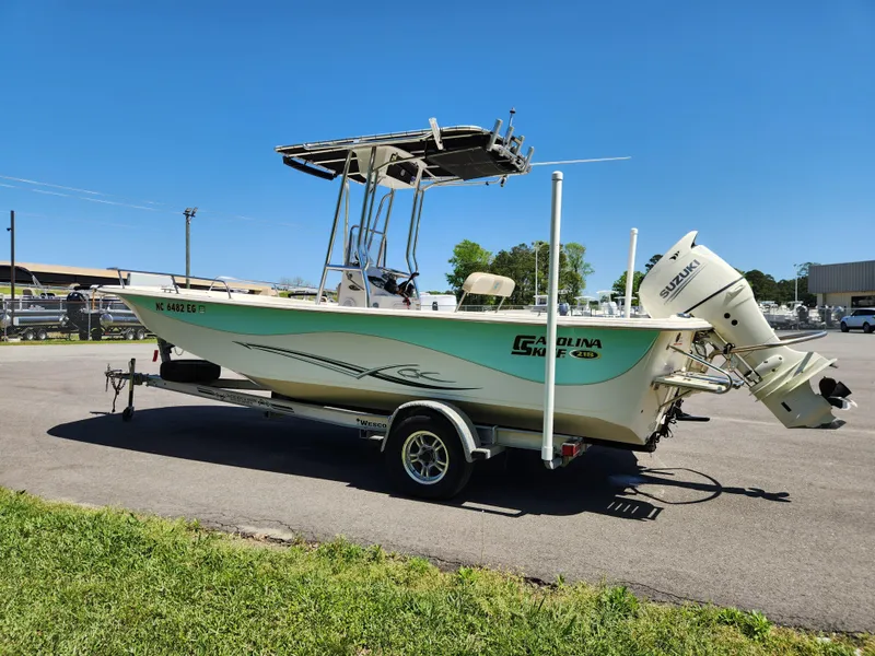 Slide: The Image of 2018 Carolina Skiff 218 DLV boat on trailer, parked outdoors under clear blue sky. - 5