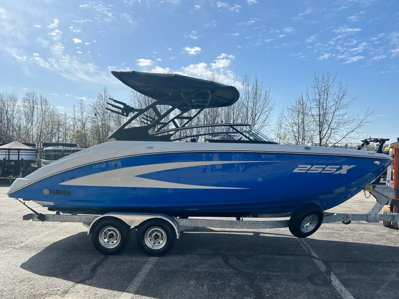 Slide: The Image of 2025 Yamaha Boats 255XD, blue and silver, on a trailer in a parking lot. - 4