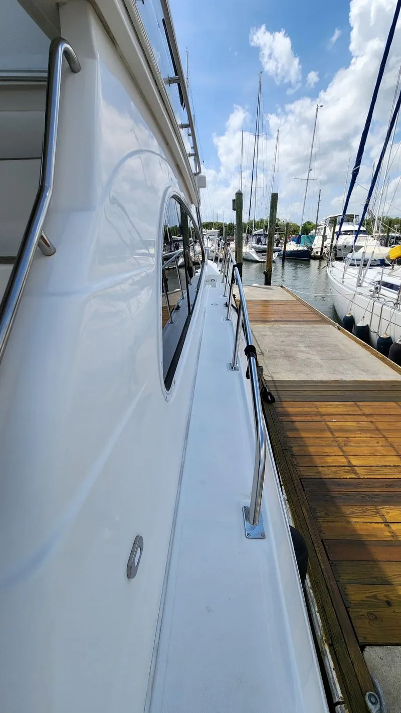 Slide: The Image of 2002 Cruisers 5000 yacht docked at marina under blue sky. - 10