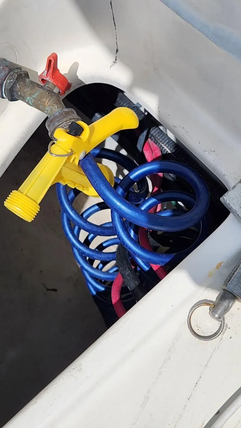 Slide: The Image of Coiled blue hose with yellow nozzle in a 2002 Cruisers 5000 boat compartment. - 15