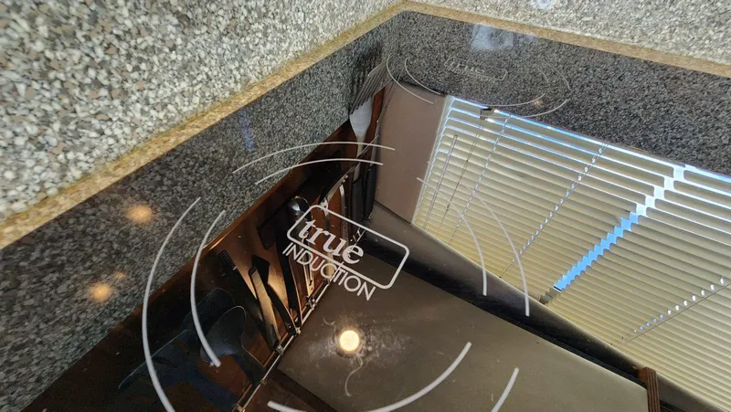 Slide: The Image of Granite countertop with True Induction cooktop, reflecting blinds and lights. - 23