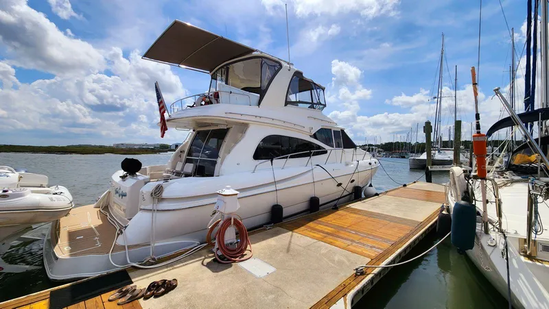 Slide: The Image of 2002 Cruisers 5000 yacht docked at marina under blue sky. - 4