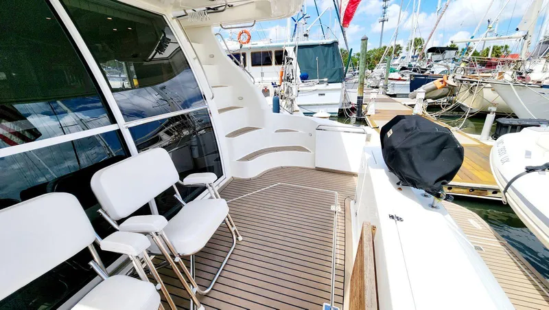 Slide: The Image of 2002 Cruisers 5000 yacht deck with seating, docked at marina under clear sky. - 7