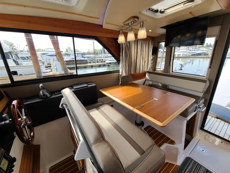 Slide: The Image of 2023 Cutwater C-30 Sedan NW Edition interior with dining area and marina view. - 12