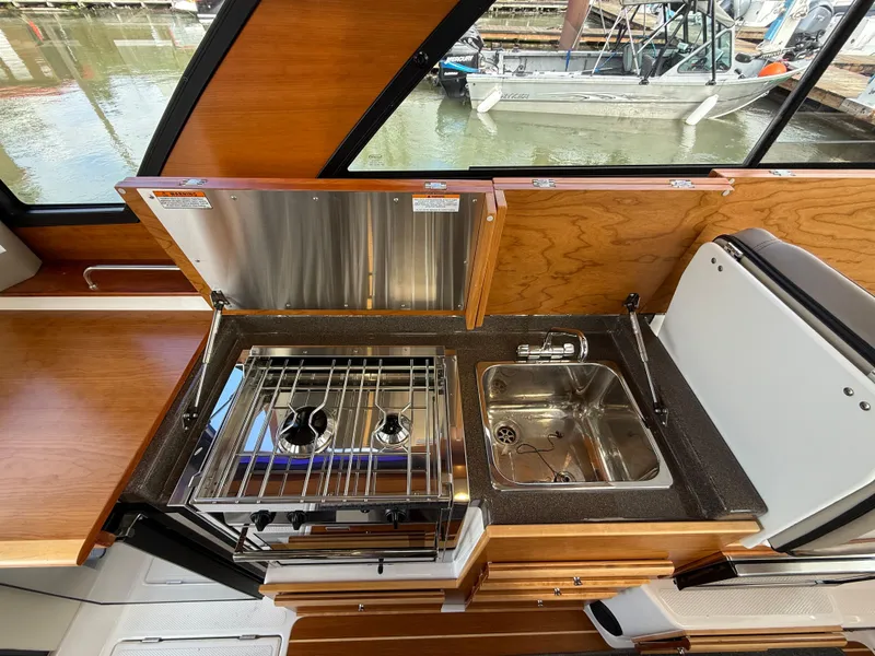 Slide: The Image of 2023 Cutwater C-30 Sedan NW Edition boat kitchen with stove and sink. - 13