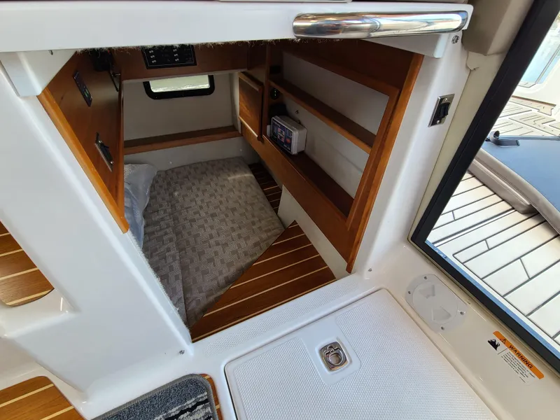 Slide: The Image of 2023 Cutwater C-30 Sedan NW Edition cabin interior with wooden shelves and cozy bedding. - 20