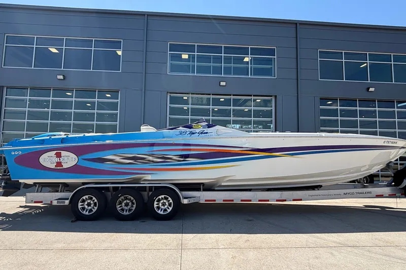 Slide: The Image of 2000 Cigarette 38' Top Gun speedboat on trailer, vibrant blue and white design. - 32
