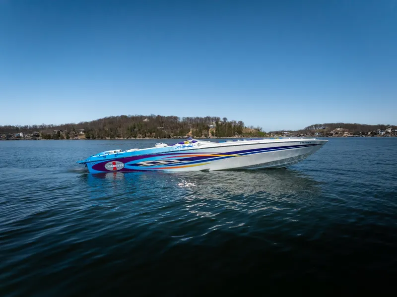 The Image of 2000 Cigarette 38' Top Gun speedboat on a calm lake under clear blue skies. - 2