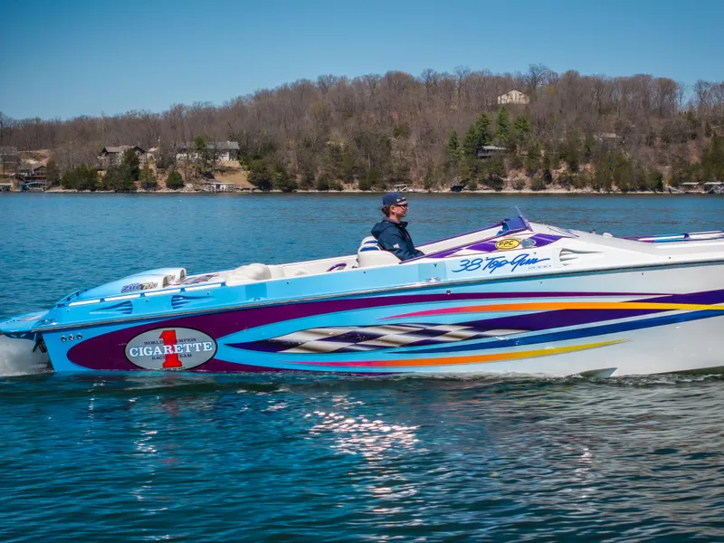 Slide: The Image of 2000 Cigarette 38' Top Gun speedboat cruising on a lake with scenic background. - 5