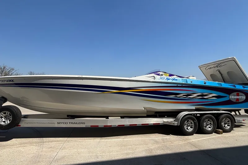 Slide: The Image of 2000 Cigarette 38' Top Gun speedboat on trailer, showcasing sleek design and vibrant graphics. - 34