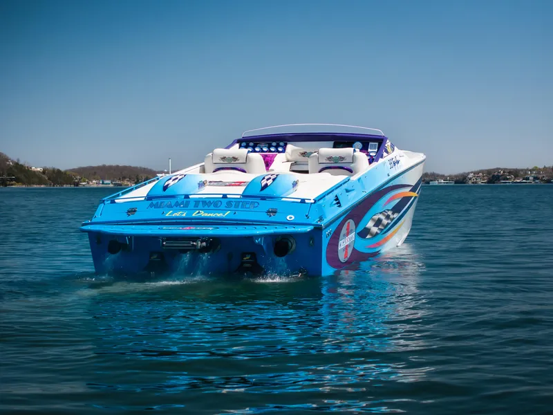 Slide: The Image of 2000 Cigarette 38' Top Gun speedboat on water, vibrant blue design, sunny day. - 7