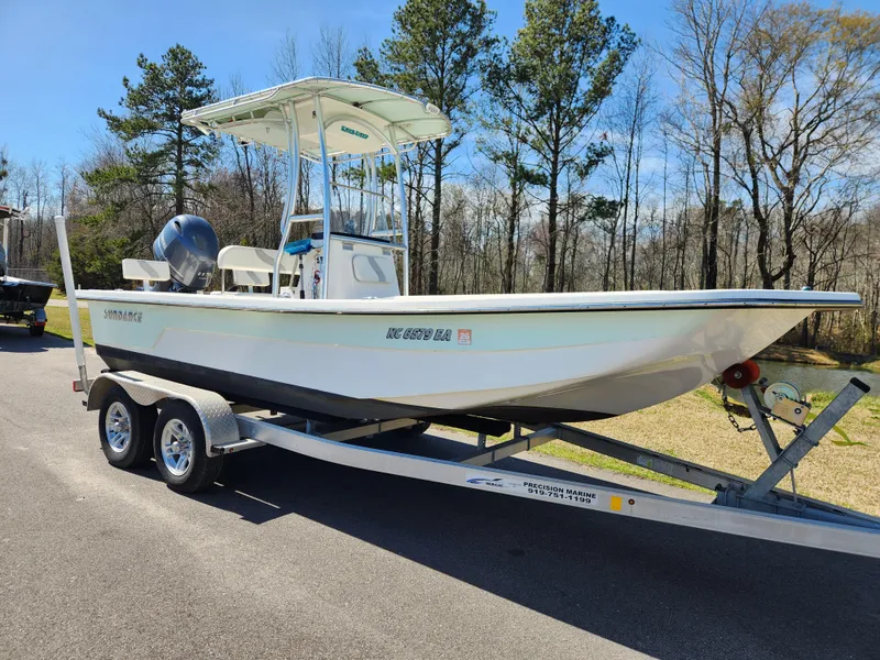 Slide: The Image of 2015 Sundance B20CCR boat on trailer, parked outdoors with trees in the background. - 1