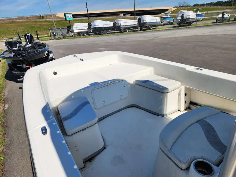 Slide: The Image of 2015 Sundance B20CCR boat interior with seating, parked near other boats. - 11