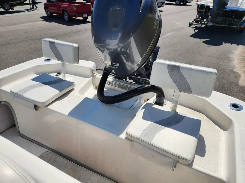 Slide: The Image of 2015 Sundance B20CCR boat with seating and outboard motor in a parking lot. - 13