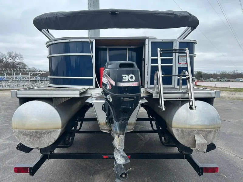 Slide: The Image of 1999 Sylvan 20 Cruise pontoon boat with outboard motor and ladder, parked on trailer. - 2