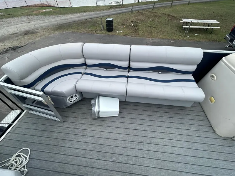 Slide: The Image of 1999 Sylvan 20 Cruise boat interior with gray and blue seating on a wooden deck. - 5