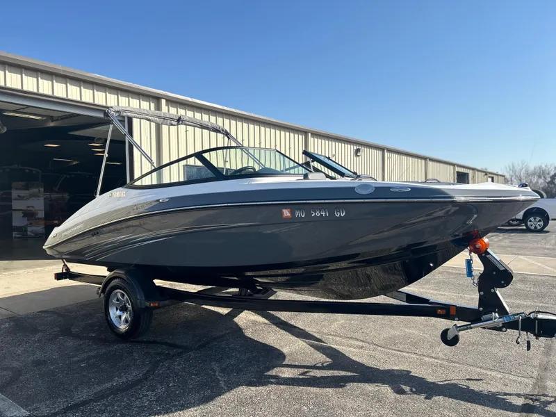 Slide: The Image of 2015 Yamaha Boats SX192 on trailer, parked outside a warehouse under clear blue sky. - 2