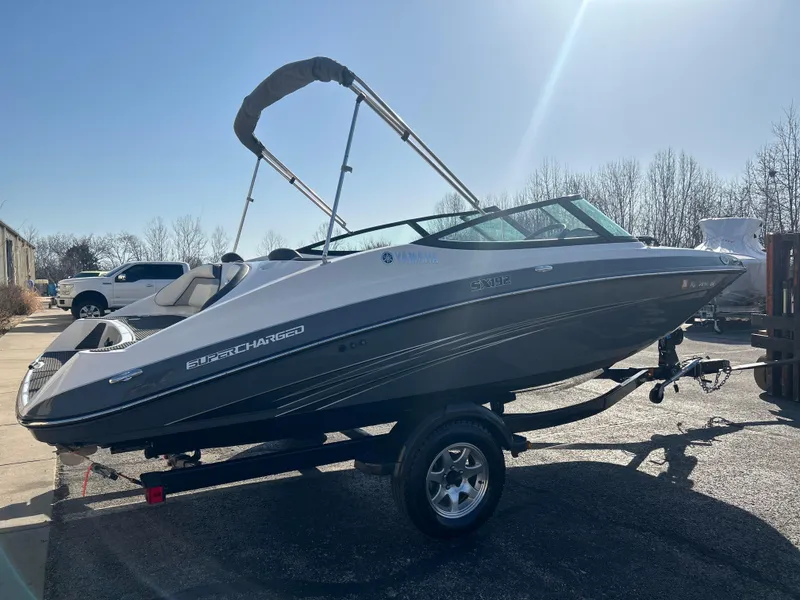 Slide: The Image of 2015 Yamaha Boats SX192 on trailer, sleek design, bimini top, parked outdoors. - 3