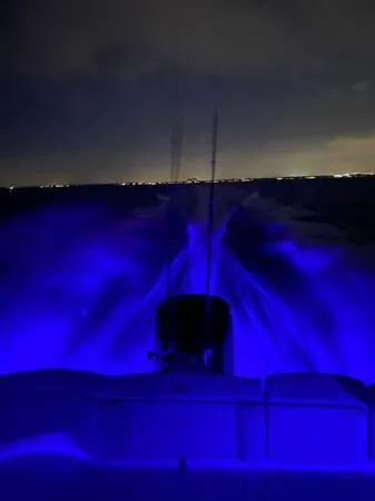 Slide: The Image of 2021 Sea Hunt Ultra 255 SE boat with blue underwater lights at night. - 10