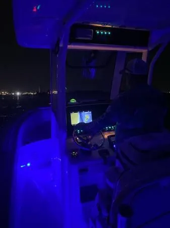 Slide: The Image of 2021 Sea Hunt Ultra 255 SE boat cockpit illuminated at night with blue LED lights. - 11
