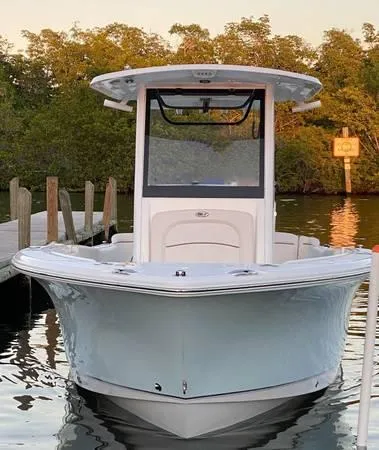 Slide: The Image of 2021 Sea Hunt Ultra 255 SE boat docked in serene waters, surrounded by lush greenery. - 2