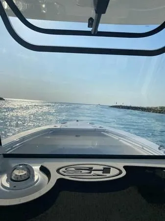 Slide: The Image of 2021 Sea Hunt Ultra 255 SE boat navigating through calm waters under a clear sky. - 6