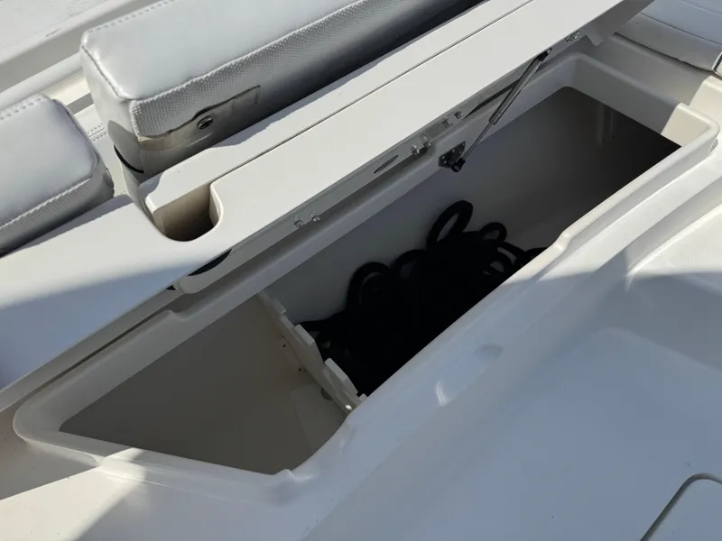Slide: The Image of 2020 Regulator 26XO boat storage compartment with open lid and coiled rope inside. - 28