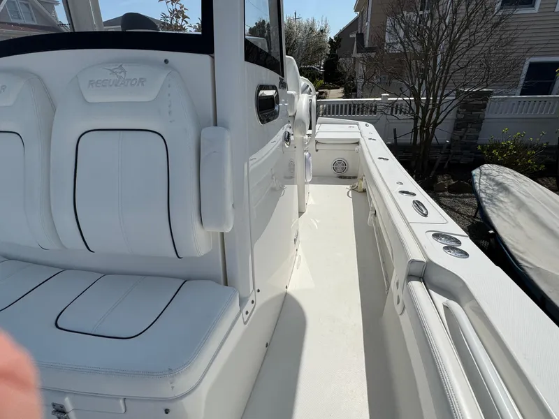 Slide: The Image of 2020 Regulator 26XO boat interior with white seating and console, docked near houses. - 37