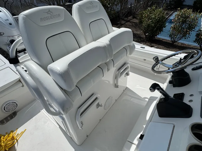 Slide: The Image of 2020 Regulator 26XO boat helm with dual white cushioned seats and steering wheel. - 40