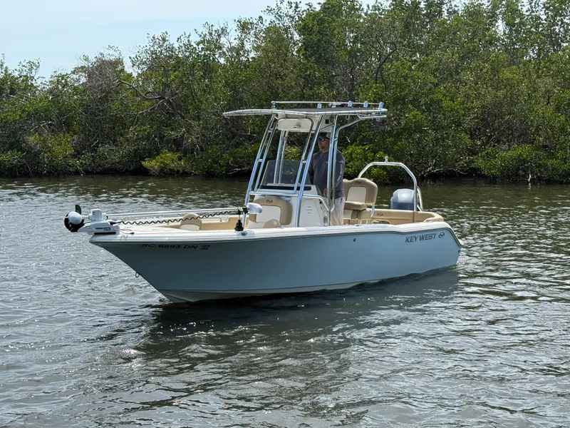 Slide: The Image of 2020 Key West 203 FS boat on calm water near lush greenery. - 2