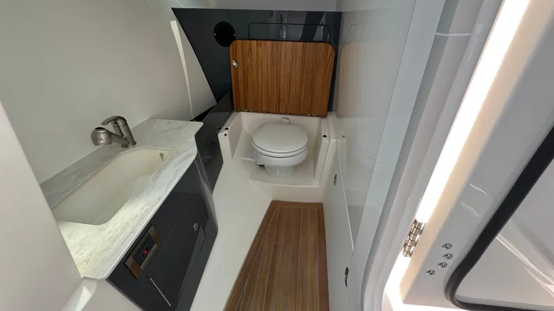Slide: The Image of 2025 Boston Whaler 330 Vantage boat bathroom with sink, toilet, and wood accents. - 18